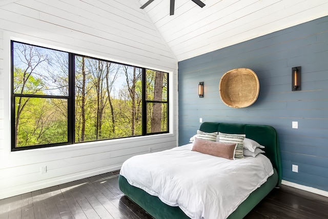 bedroom with wooden walls, dark wood-style flooring, and lofted ceiling