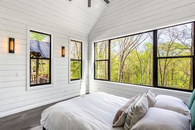bedroom featuring baseboards, wood walls, wood finished floors, and vaulted ceiling