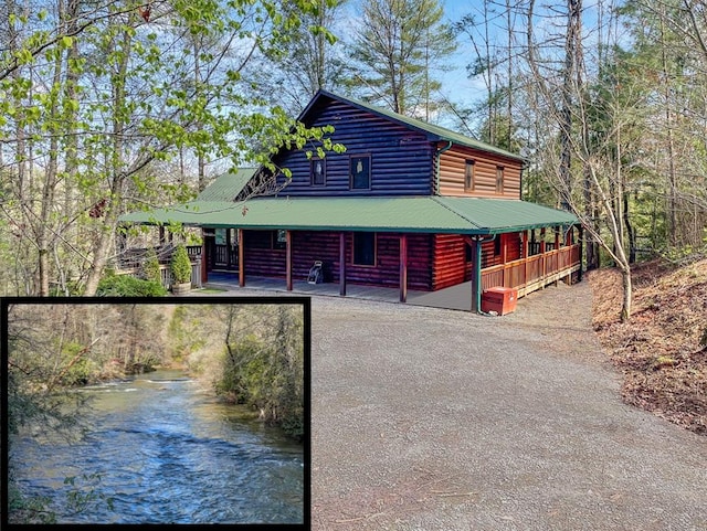 view of front of house with driveway, metal roof, and a porch