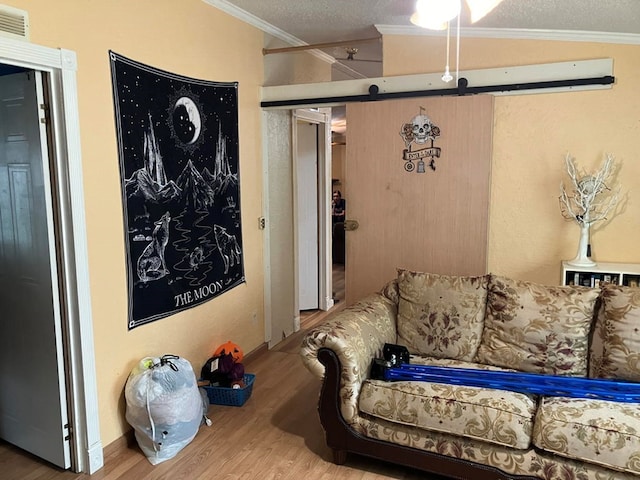 living room featuring a textured ceiling, vaulted ceiling, crown molding, wood-type flooring, and a barn door