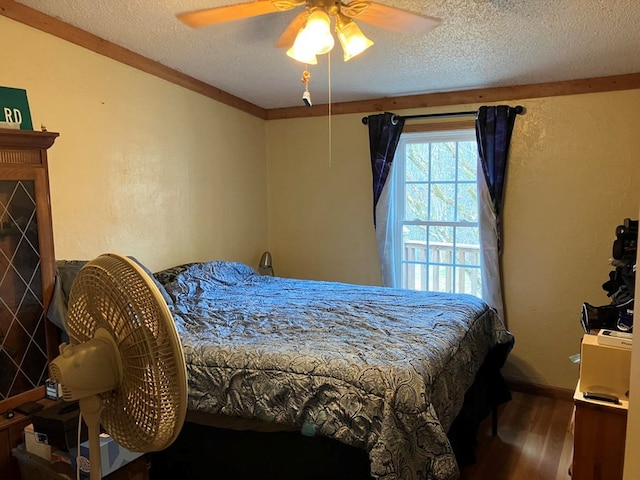 bedroom with hardwood / wood-style flooring, ceiling fan, ornamental molding, and a textured ceiling