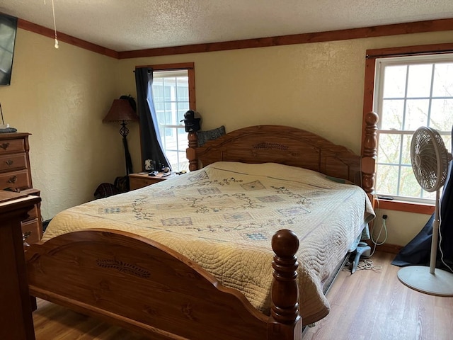 bedroom with wood-type flooring, a textured ceiling, and multiple windows