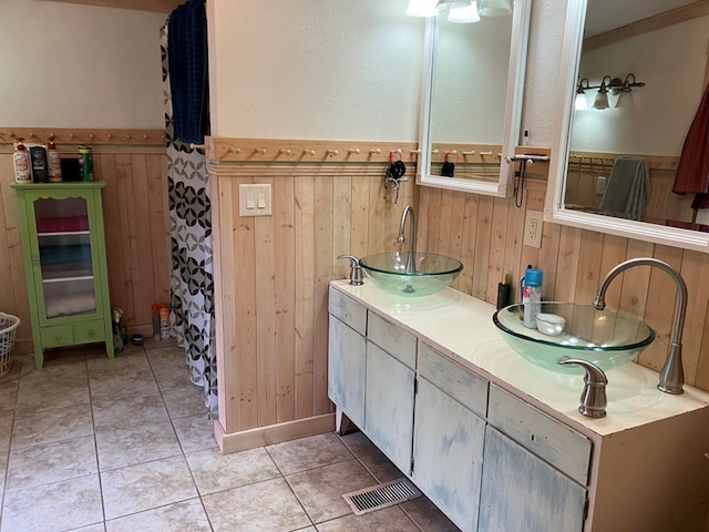 bathroom featuring tile patterned flooring, vanity, and wood walls