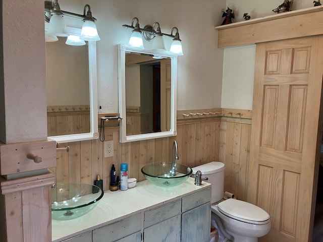 bathroom featuring vanity, toilet, and wood walls