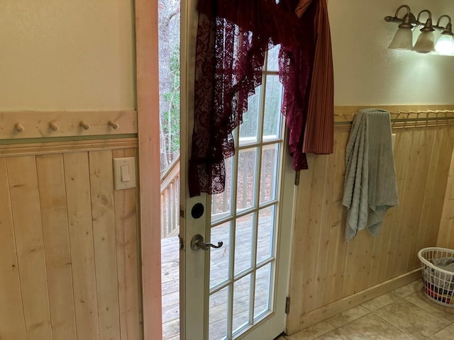 doorway featuring wood walls and light tile patterned floors