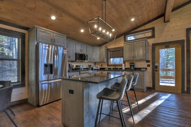 kitchen with lofted ceiling with beams, hanging light fixtures, dark hardwood / wood-style floors, a kitchen island, and stainless steel appliances