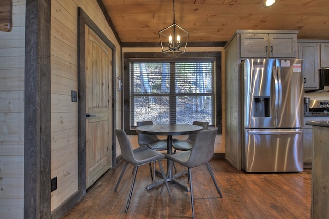 dining space featuring dark hardwood / wood-style flooring, wooden walls, an inviting chandelier, and wooden ceiling