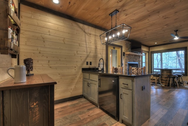 kitchen with wooden ceiling, dark wood-type flooring, pendant lighting, and wood walls