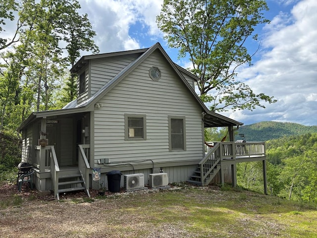 rear view of property featuring a wooden deck, stairs, and ac unit