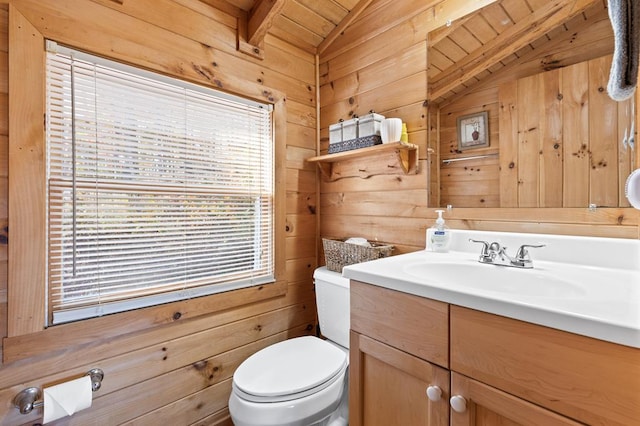 half bathroom featuring toilet, wood walls, vanity, and vaulted ceiling