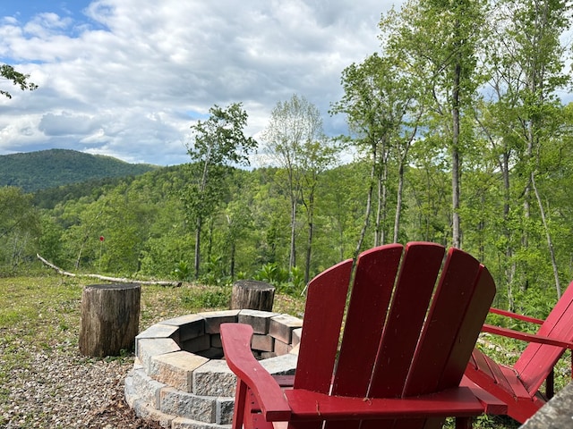 exterior space featuring an outdoor fire pit and a forest view