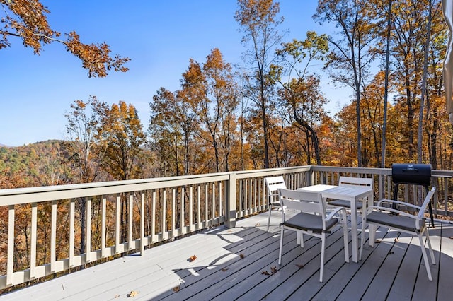 wooden terrace with outdoor dining area and a grill