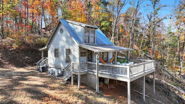 rear view of house with metal roof, a wooden deck, and central air condition unit