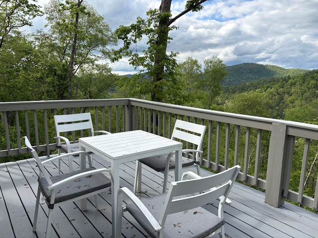 wooden terrace featuring a forest view and outdoor dining space