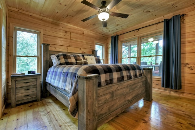 bedroom with ceiling fan, light hardwood / wood-style flooring, wood ceiling, and wooden walls