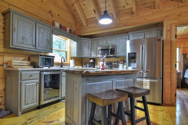 kitchen with a center island, wooden ceiling, wine cooler, wood walls, and appliances with stainless steel finishes