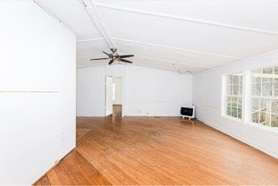 unfurnished living room featuring lofted ceiling with beams, heating unit, ceiling fan, and wood finished floors