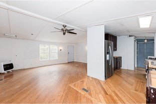 unfurnished living room featuring heating unit, light wood-style flooring, and a ceiling fan