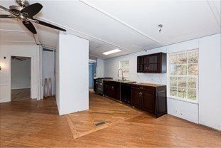 bar featuring light wood-type flooring, a barn door, a ceiling fan, and lofted ceiling