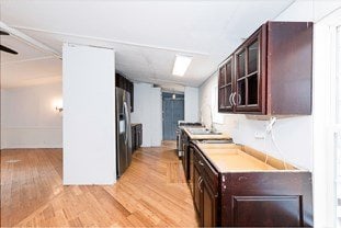 kitchen with stainless steel fridge, glass insert cabinets, light wood-style flooring, and light countertops