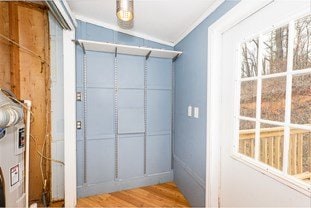 entryway with crown molding and wood finished floors