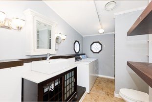 bathroom featuring toilet, baseboards, washer and clothes dryer, and vanity