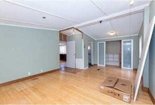 unfurnished living room featuring baseboards, vaulted ceiling, and wood finished floors