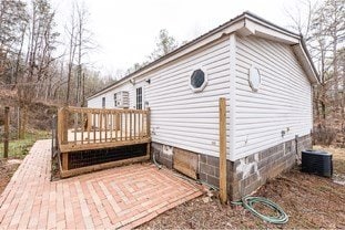 view of side of property featuring a deck, central AC unit, and crawl space