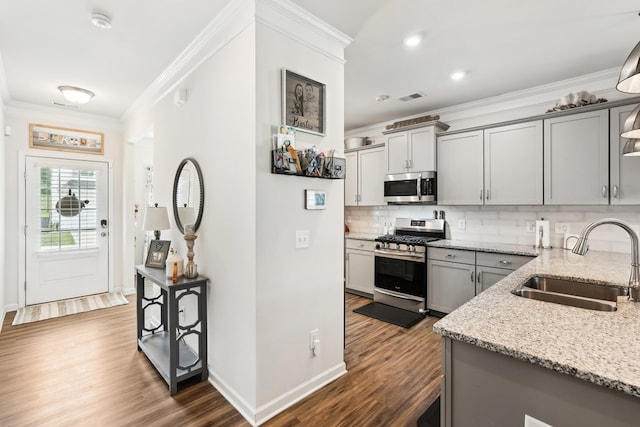 kitchen with gray cabinets, appliances with stainless steel finishes, ornamental molding, and a sink
