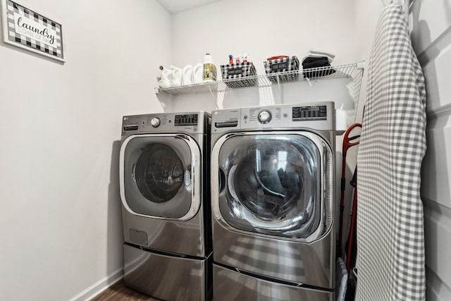 clothes washing area featuring baseboards, laundry area, wood finished floors, and washer and clothes dryer