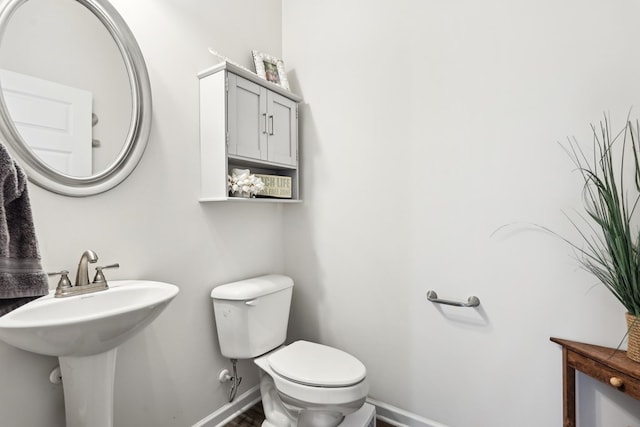 bathroom with baseboards, a sink, wood finished floors, and toilet