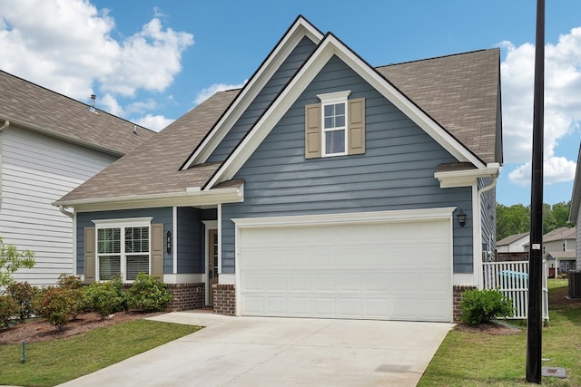 view of front facade featuring central AC unit, a shingled roof, fence, and concrete driveway