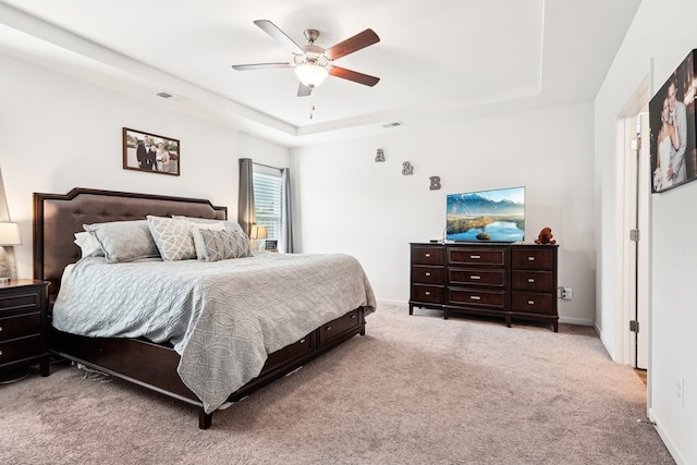 bedroom featuring carpet flooring, a ceiling fan, a tray ceiling, and visible vents