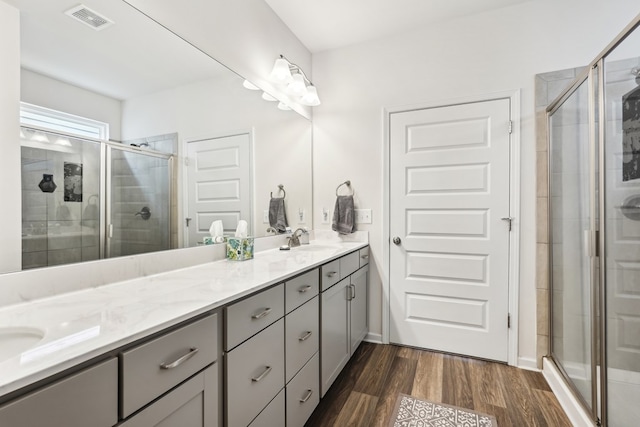 bathroom with visible vents, a sink, double vanity, and a shower stall