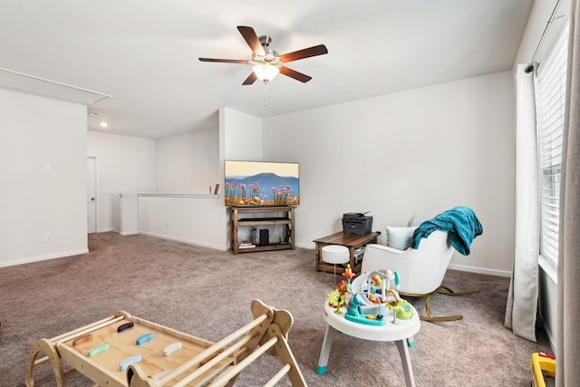 living area featuring a ceiling fan, baseboards, carpet, and attic access