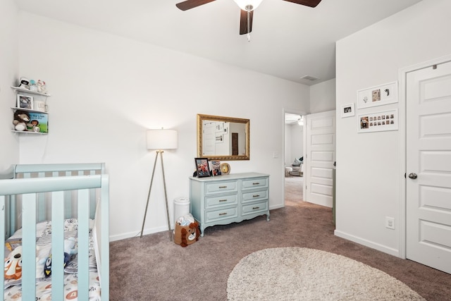 carpeted bedroom with a crib, baseboards, ceiling fan, and visible vents