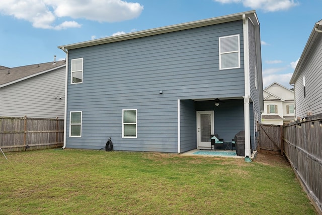 back of house with a fenced backyard, a lawn, and a patio area