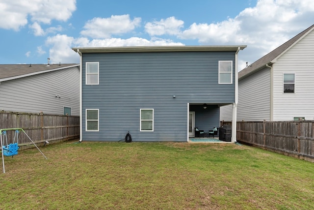 rear view of property featuring a lawn, a fenced backyard, and a patio