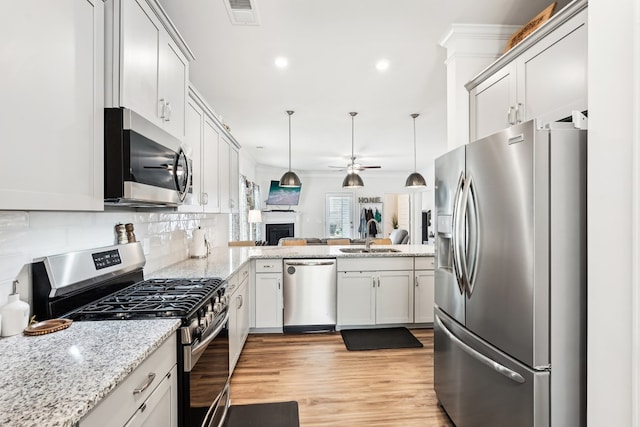 kitchen with visible vents, open floor plan, ceiling fan, tasteful backsplash, and appliances with stainless steel finishes