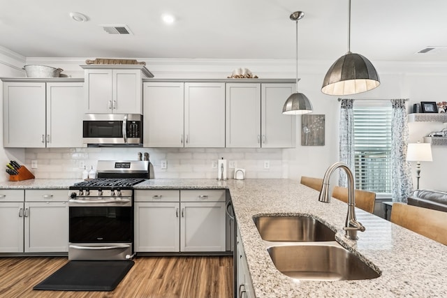 kitchen with a sink, stainless steel appliances, tasteful backsplash, visible vents, and ornamental molding