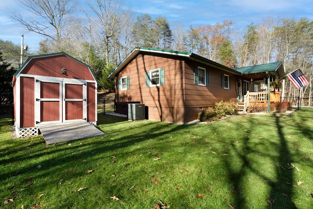 rear view of house with a lawn, a wooden deck, central AC unit, and a storage unit