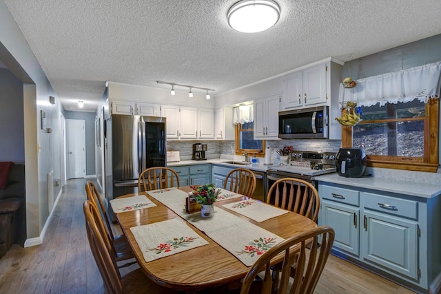 dining space with sink, a textured ceiling, and light wood-type flooring