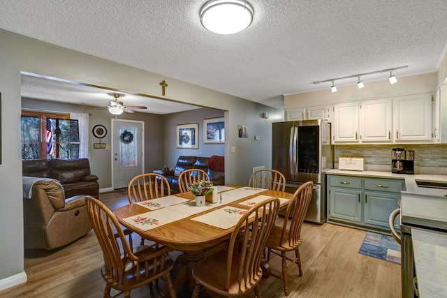 dining space with a textured ceiling, light hardwood / wood-style floors, ceiling fan, and rail lighting