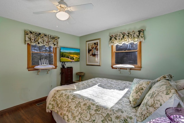 bedroom with ceiling fan, dark hardwood / wood-style floors, and a textured ceiling