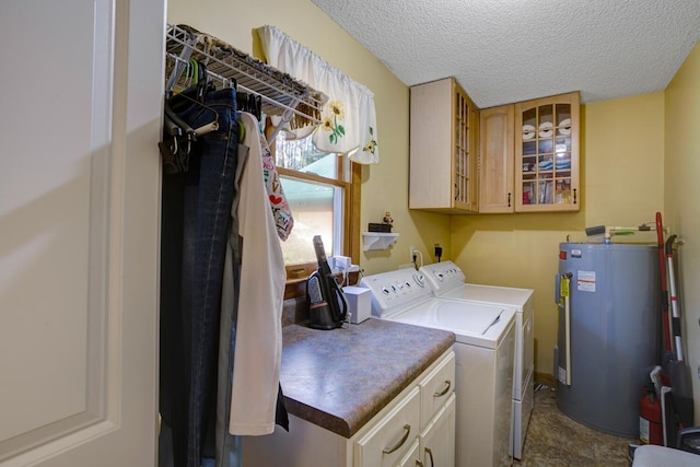 clothes washing area with washing machine and dryer, electric water heater, cabinets, and a textured ceiling