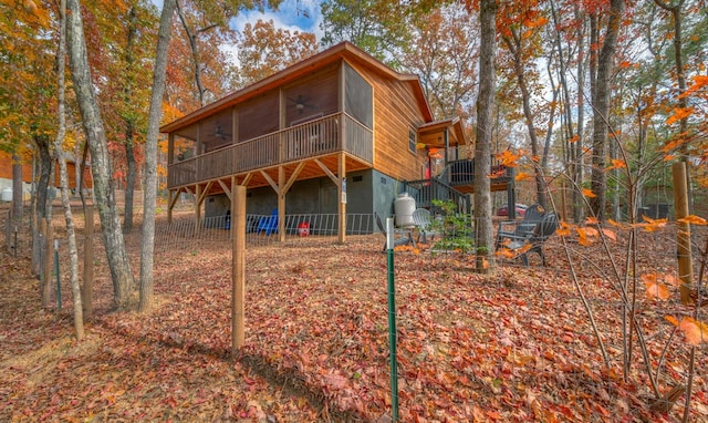 rear view of property featuring a sunroom and ceiling fan