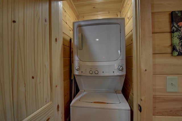 laundry room with stacked washer / dryer and wood walls