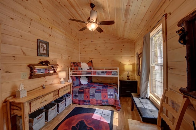 bedroom featuring wood walls, ceiling fan, light hardwood / wood-style floors, and vaulted ceiling