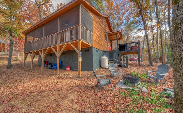 rear view of house featuring a sunroom, ceiling fan, and an outdoor fire pit