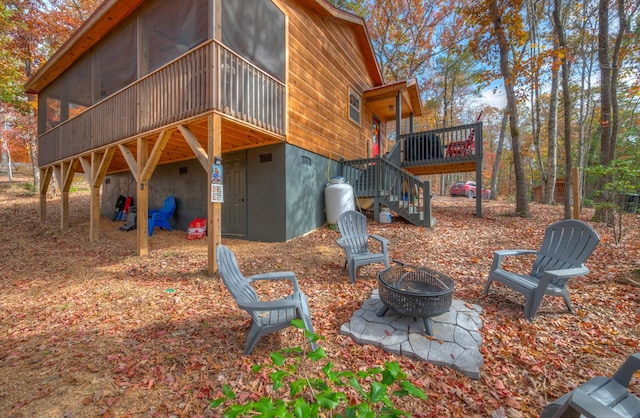 rear view of property with a fire pit, a sunroom, and a deck